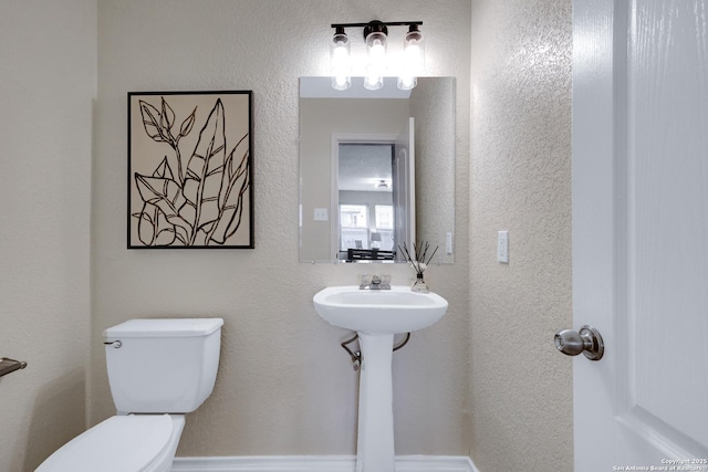 bathroom with a sink, a textured wall, and toilet