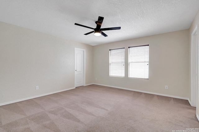 empty room featuring a textured ceiling, ceiling fan, baseboards, and light colored carpet