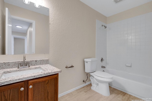 full bathroom featuring a textured wall, vanity, toilet, and wood finished floors