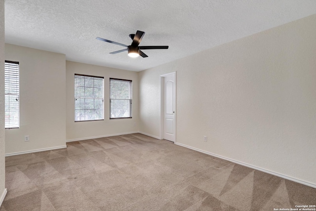 unfurnished room featuring baseboards, a ceiling fan, a textured wall, a textured ceiling, and carpet flooring