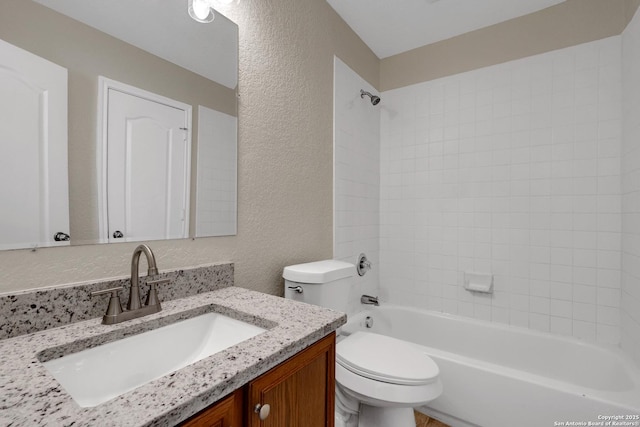 bathroom with toilet, vanity, tub / shower combination, and a textured wall