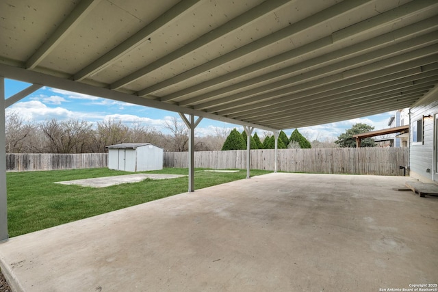 view of patio featuring a storage shed, a fenced backyard, and an outbuilding