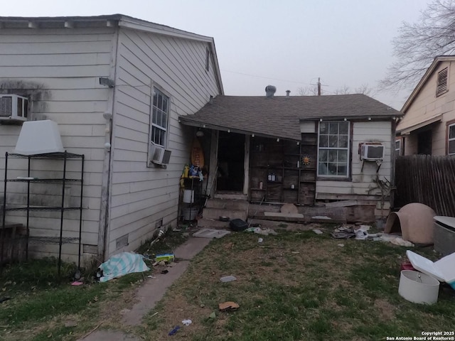 rear view of property with a shingled roof and cooling unit