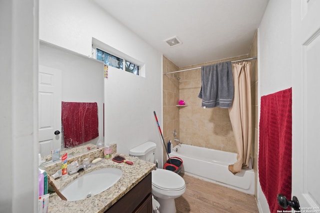 bathroom with toilet, wood finished floors, vanity, visible vents, and shower / bath combo with shower curtain