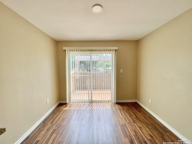 spare room featuring baseboards and wood finished floors