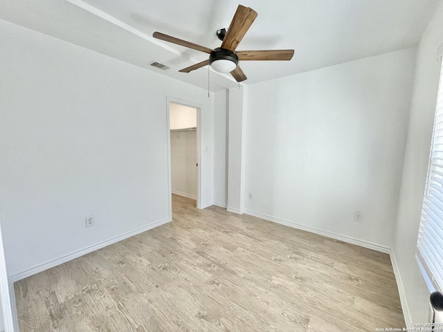 empty room with light wood-style floors, baseboards, visible vents, and ceiling fan