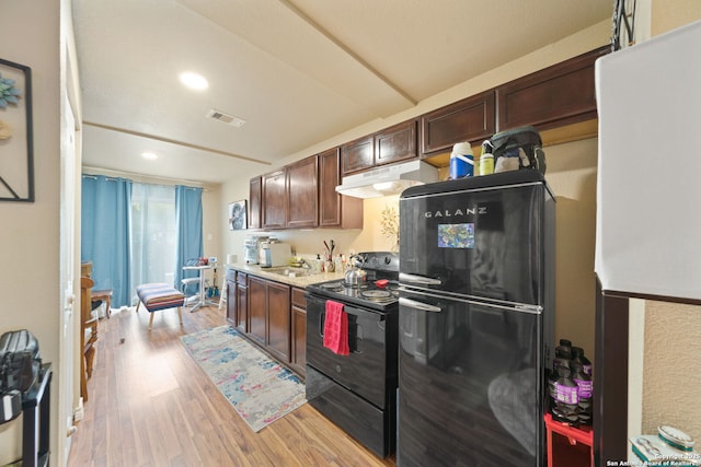 kitchen with under cabinet range hood, visible vents, light countertops, light wood-type flooring, and black appliances