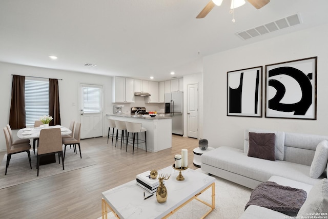 living room with light wood-type flooring, visible vents, ceiling fan, and recessed lighting