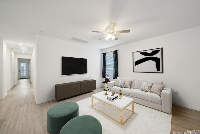 living area with light wood finished floors, attic access, visible vents, baseboards, and a ceiling fan