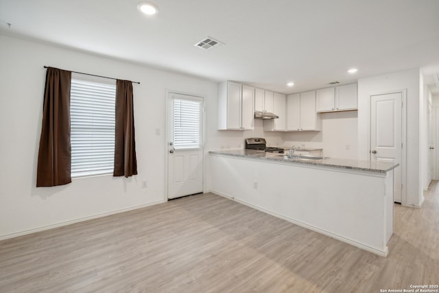 kitchen with recessed lighting, visible vents, a peninsula, light wood-type flooring, and stainless steel gas range oven