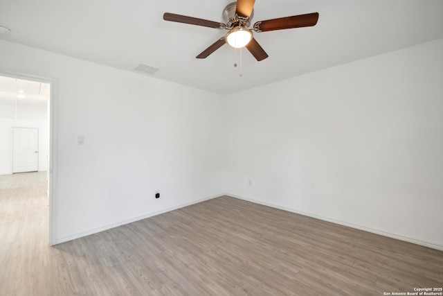 spare room with attic access, visible vents, baseboards, a ceiling fan, and light wood-type flooring