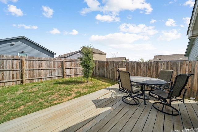 deck featuring a fenced backyard, outdoor dining area, and a lawn