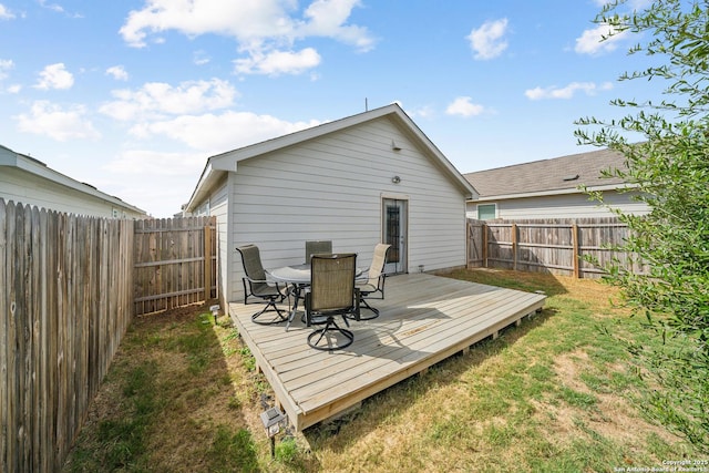 rear view of house with a fenced backyard, a lawn, and a wooden deck