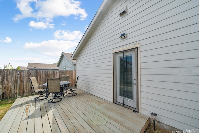 wooden terrace with outdoor dining space and fence