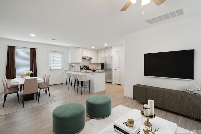 living area featuring a ceiling fan, light wood-type flooring, visible vents, and recessed lighting