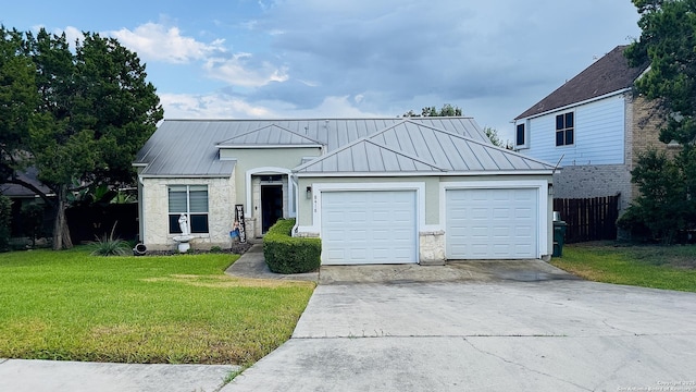 ranch-style house with a front yard, a standing seam roof, metal roof, a garage, and driveway