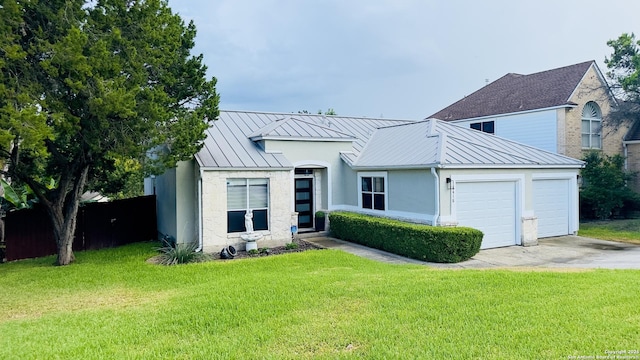 view of front of house featuring stucco siding, a standing seam roof, metal roof, a garage, and a front lawn