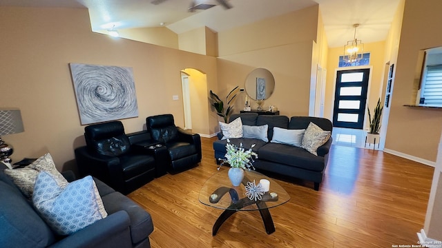 living room featuring baseboards, arched walkways, wood finished floors, an inviting chandelier, and vaulted ceiling