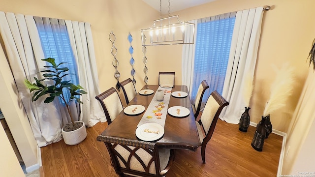 dining space with a notable chandelier, baseboards, and wood finished floors