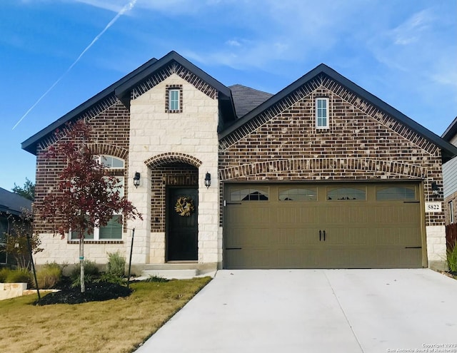 french country style house featuring a garage, brick siding, and driveway