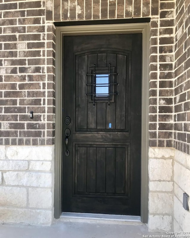 view of exterior entry featuring brick siding