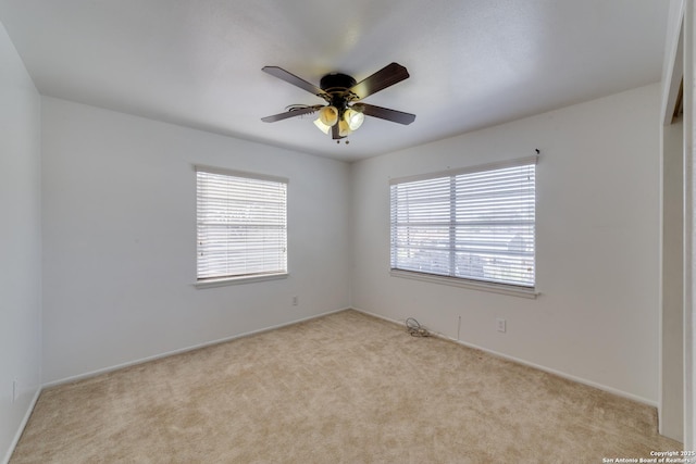 empty room featuring a ceiling fan, a wealth of natural light, and carpet