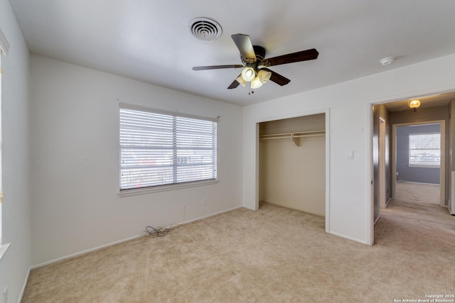 unfurnished bedroom featuring a ceiling fan, visible vents, a closet, and light colored carpet