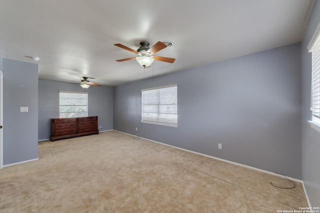 carpeted empty room with ceiling fan, a wealth of natural light, and baseboards