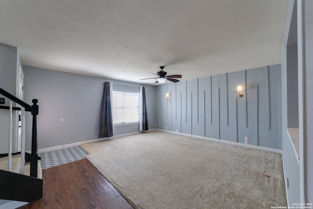 unfurnished living room featuring ceiling fan, carpet floors, a textured ceiling, and baseboards