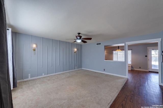 unfurnished room with ceiling fan, dark wood-type flooring, visible vents, and baseboards