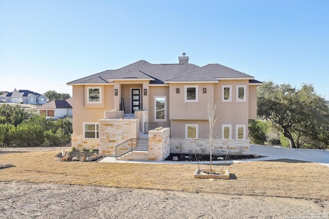 view of front facade featuring stone siding, a chimney, and stucco siding