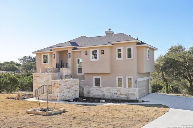 view of front of property featuring a chimney, stucco siding, an attached garage, stone siding, and driveway