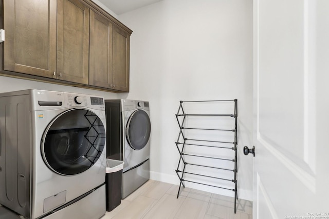 washroom featuring cabinet space, baseboards, and separate washer and dryer