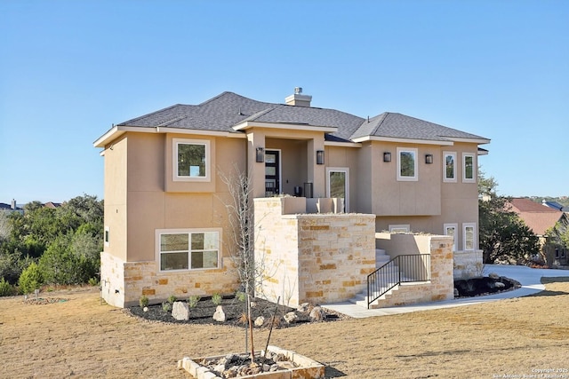 view of front of home featuring stone siding, a chimney, roof with shingles, and stucco siding