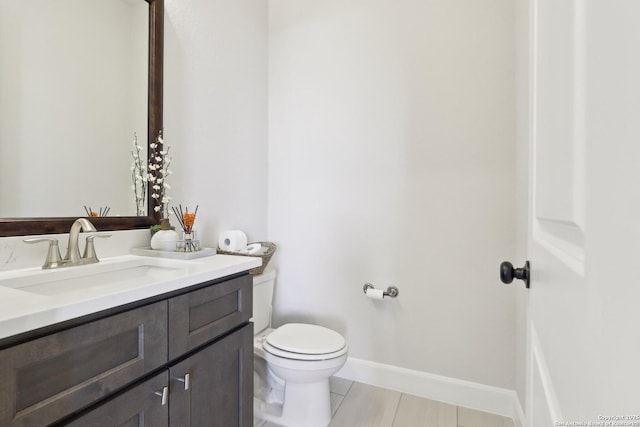 bathroom with toilet, tile patterned flooring, baseboards, and vanity