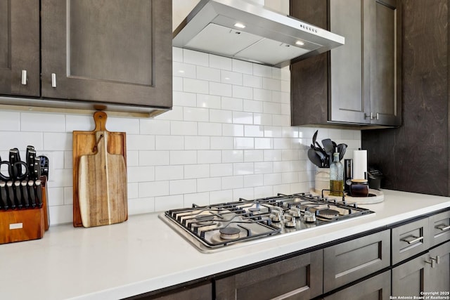 kitchen with tasteful backsplash, ventilation hood, dark brown cabinets, light countertops, and stainless steel gas stovetop