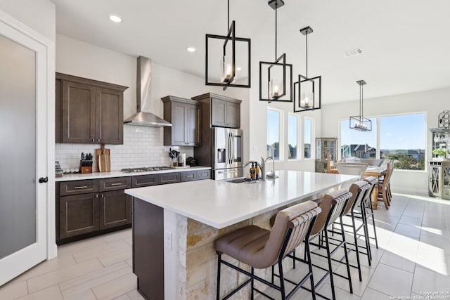 kitchen with tasteful backsplash, visible vents, appliances with stainless steel finishes, a sink, and wall chimney exhaust hood