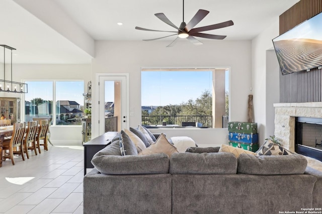 living room featuring ceiling fan with notable chandelier and a high end fireplace