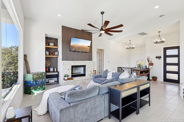 living area with recessed lighting, ceiling fan with notable chandelier, visible vents, and a stone fireplace