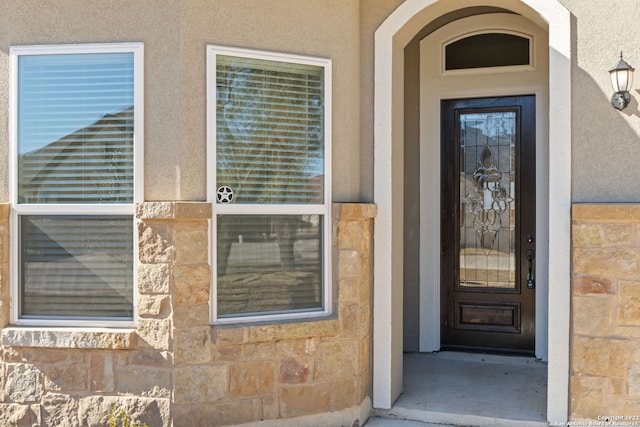 property entrance featuring stone siding and stucco siding