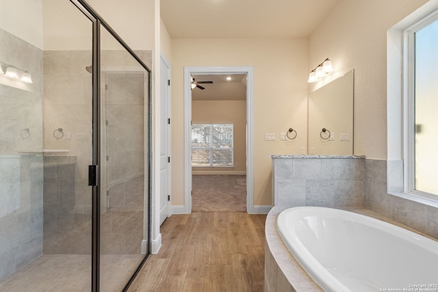 full bathroom with wood finished floors, a stall shower, a garden tub, and baseboards