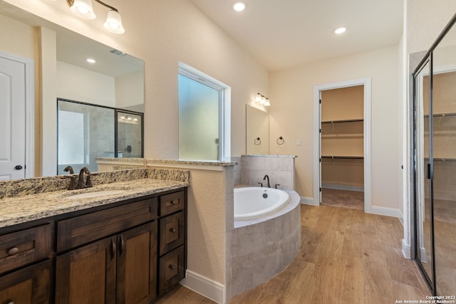 full bath with a garden tub, a spacious closet, wood finished floors, and visible vents