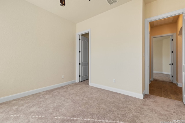 carpeted spare room featuring visible vents, ceiling fan, and baseboards