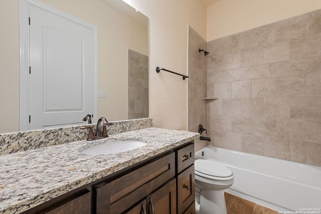 bathroom featuring a textured wall, toilet, wood finished floors, vanity, and washtub / shower combination