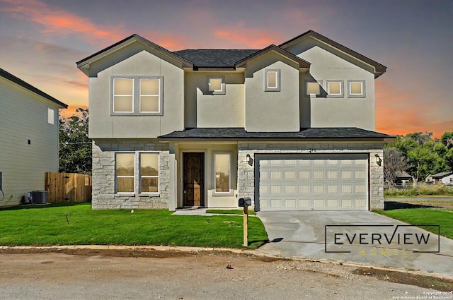 view of front of house featuring a garage, driveway, stone siding, fence, and a yard