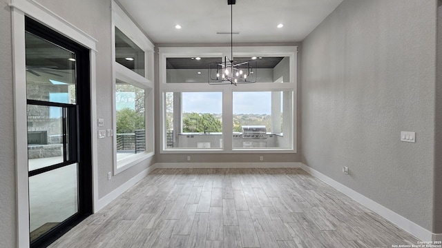 interior space featuring a chandelier, a textured wall, recessed lighting, wood finished floors, and baseboards