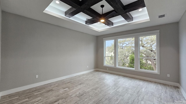 spare room with coffered ceiling, visible vents, baseboards, light wood-type flooring, and beamed ceiling