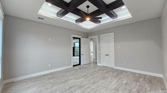 unfurnished room featuring coffered ceiling, light wood-type flooring, visible vents, and baseboards