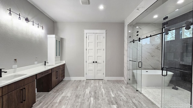 bathroom with a stall shower, visible vents, a sink, and wood finished floors