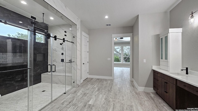 full bath with wood finished floors, vanity, baseboards, visible vents, and a shower stall